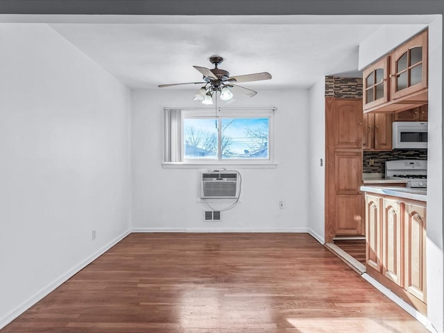 unfurnished dining area featuring ceiling fan, light wood-type flooring, and a wall unit AC