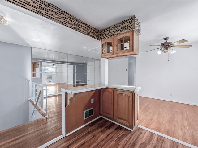 kitchen featuring kitchen peninsula, ceiling fan, and dark wood-type flooring