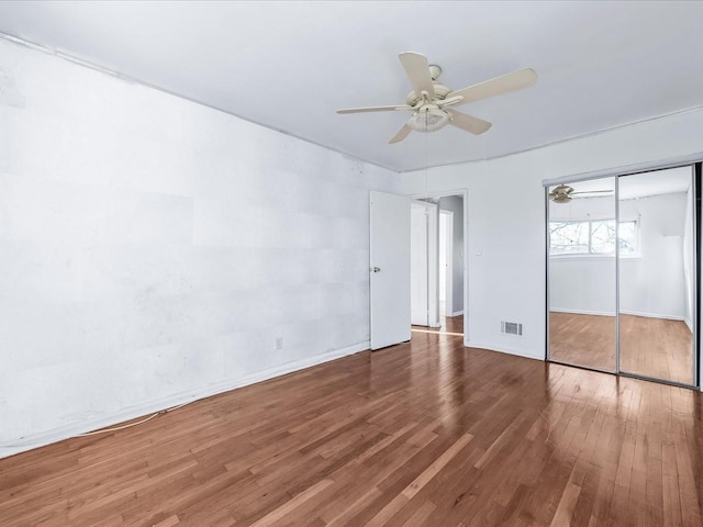 unfurnished bedroom featuring hardwood / wood-style floors, ceiling fan, and a closet