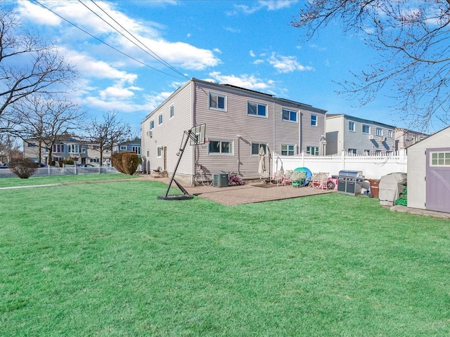 rear view of house with a storage unit, a patio area, a yard, and central air condition unit