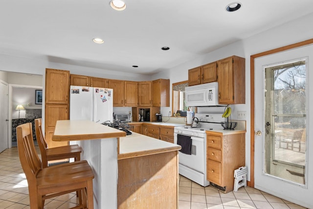 kitchen with white appliances, a center island, light tile patterned floors, a kitchen breakfast bar, and sink