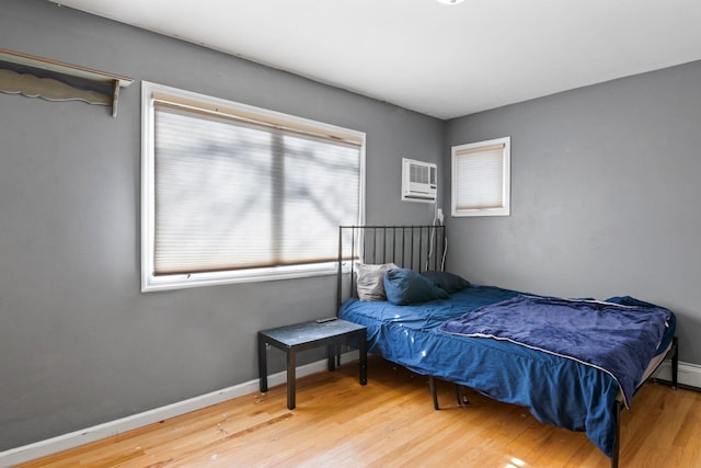 bedroom featuring wood-type flooring and a wall mounted air conditioner