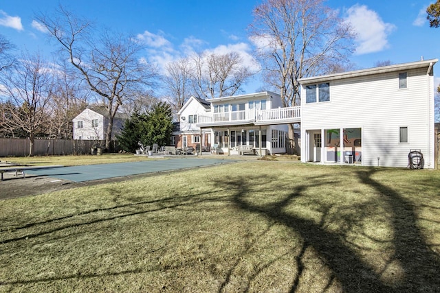 rear view of house with a balcony, a yard, and a covered pool