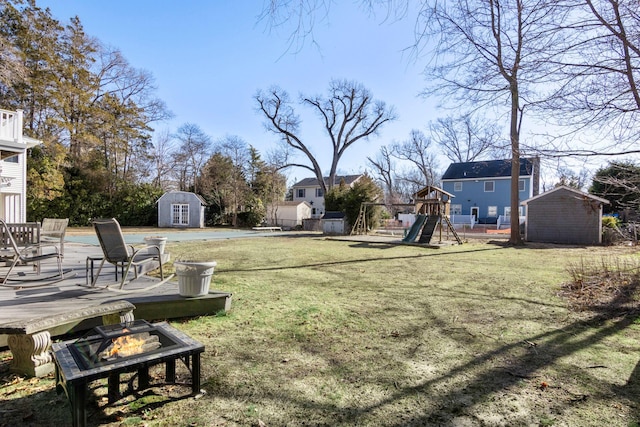 view of yard featuring a fire pit, a playground, and a storage unit