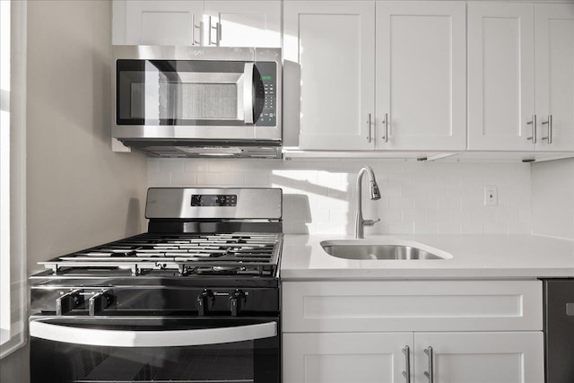 kitchen with white cabinets, decorative backsplash, sink, and appliances with stainless steel finishes