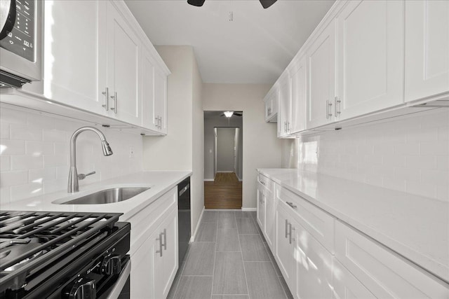 kitchen featuring backsplash, white cabinets, sink, light tile patterned floors, and black dishwasher