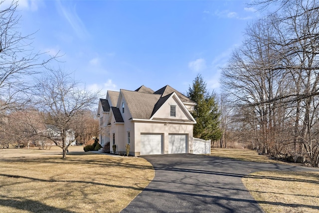 view of property exterior featuring a shingled roof, aphalt driveway, stucco siding, a yard, and an attached garage