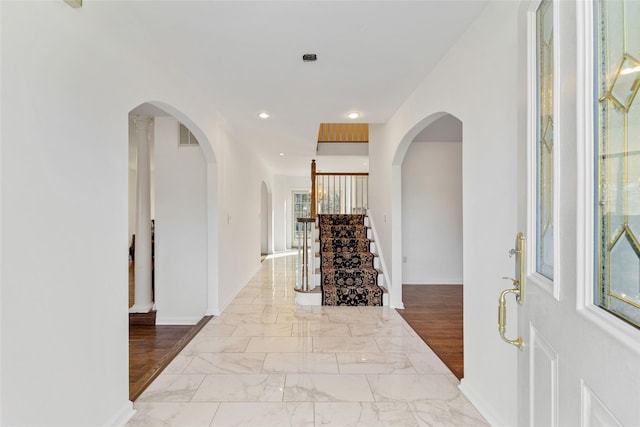 foyer entrance featuring recessed lighting, arched walkways, marble finish floor, and stairs