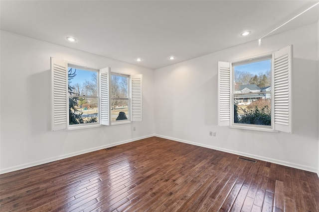 empty room featuring visible vents, plenty of natural light, and hardwood / wood-style flooring