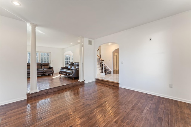 interior space with arched walkways, visible vents, baseboards, and hardwood / wood-style floors