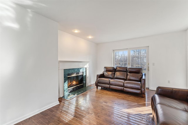 living room with baseboards, a high end fireplace, and hardwood / wood-style flooring