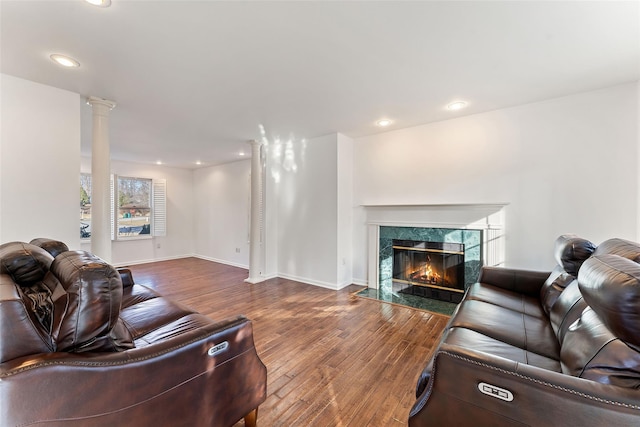 living area featuring decorative columns, a fireplace, recessed lighting, and wood-type flooring