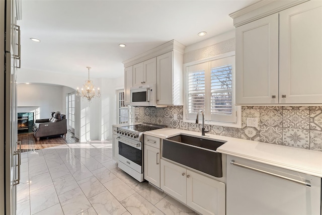 kitchen with white microwave, a sink, stainless steel stove, a glass covered fireplace, and marble finish floor