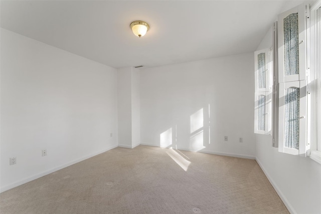 carpeted spare room featuring visible vents, baseboards, and a wealth of natural light