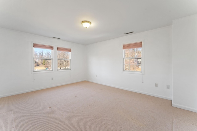 spare room featuring visible vents, a wealth of natural light, and light carpet