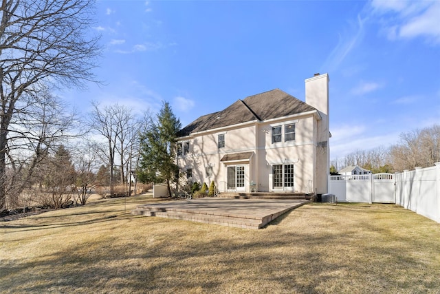 back of house featuring a gate, fence, cooling unit, a chimney, and a patio area