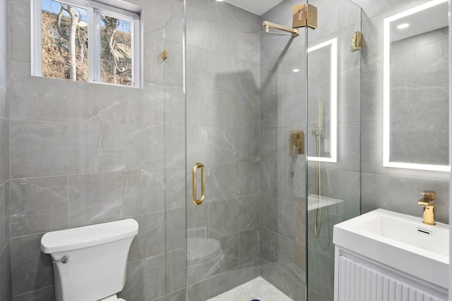 bathroom with a shower with shower door, toilet, and vanity