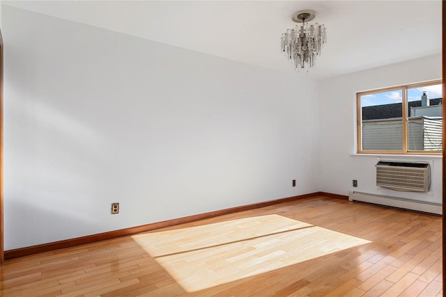 spare room with a notable chandelier, light wood-type flooring, baseboard heating, and an AC wall unit