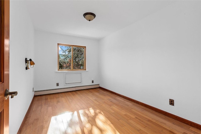 empty room featuring light wood-type flooring and a baseboard heating unit