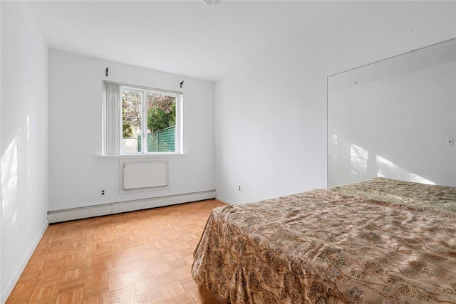 bedroom with light parquet floors and a baseboard radiator