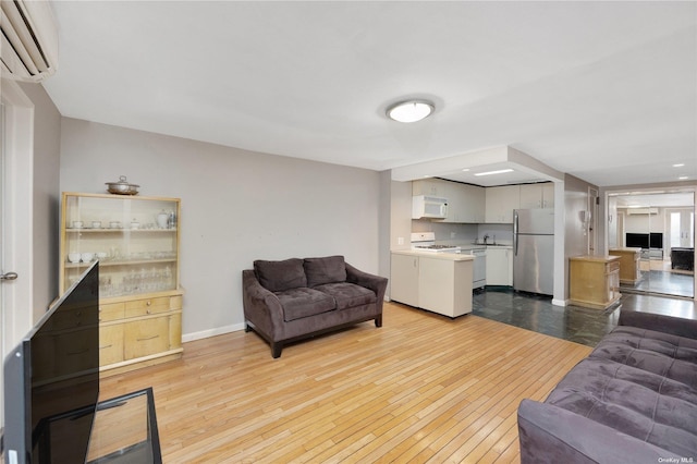 living room with light wood-type flooring, sink, and a wall unit AC