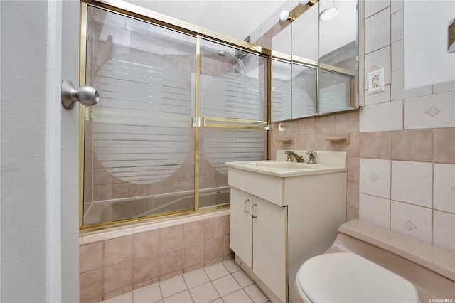 full bathroom featuring combined bath / shower with glass door, vanity, tile walls, tile patterned flooring, and toilet