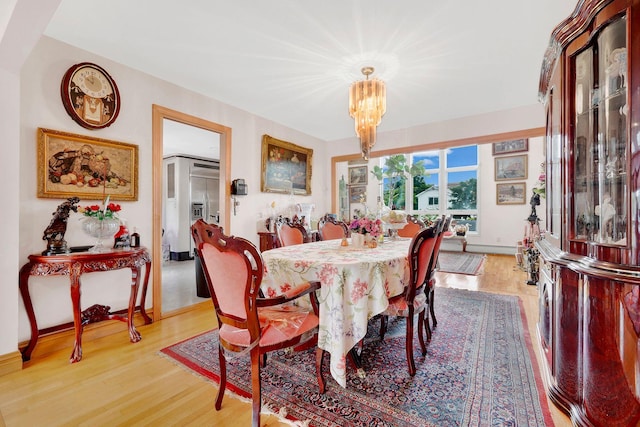 dining space with an inviting chandelier and light hardwood / wood-style flooring