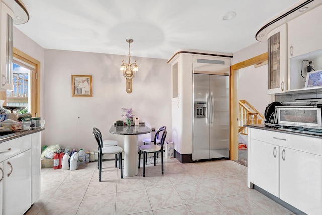 kitchen featuring stainless steel built in refrigerator, pendant lighting, and white cabinets