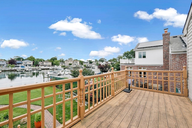 wooden terrace with a yard and a water view