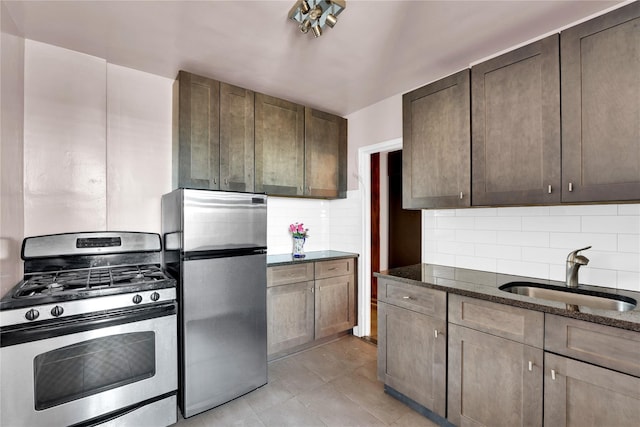 kitchen with appliances with stainless steel finishes, tasteful backsplash, dark stone countertops, sink, and dark brown cabinets