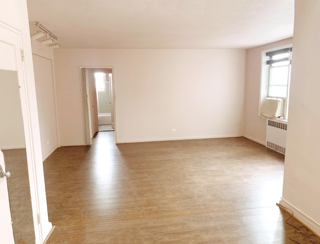 spare room featuring radiator and light hardwood / wood-style flooring