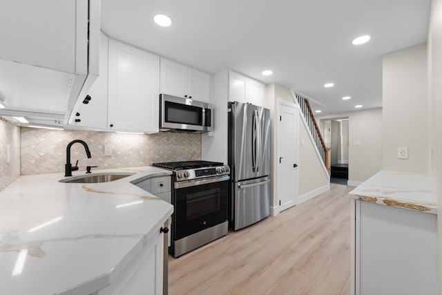 kitchen featuring sink, appliances with stainless steel finishes, white cabinetry, light stone counters, and tasteful backsplash