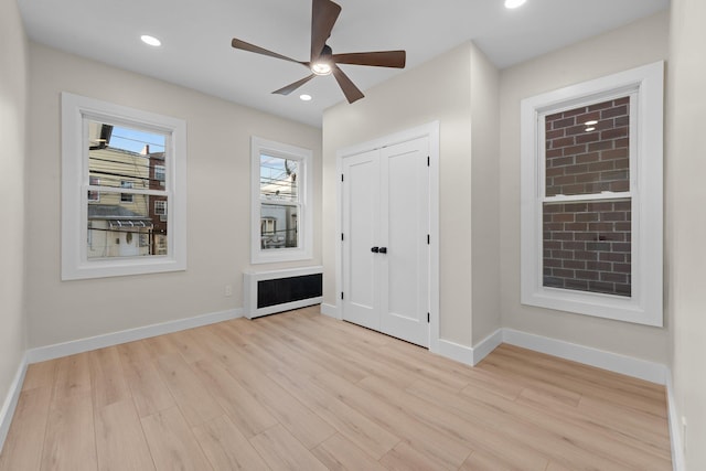 unfurnished bedroom featuring a closet, radiator, ceiling fan, and light hardwood / wood-style floors