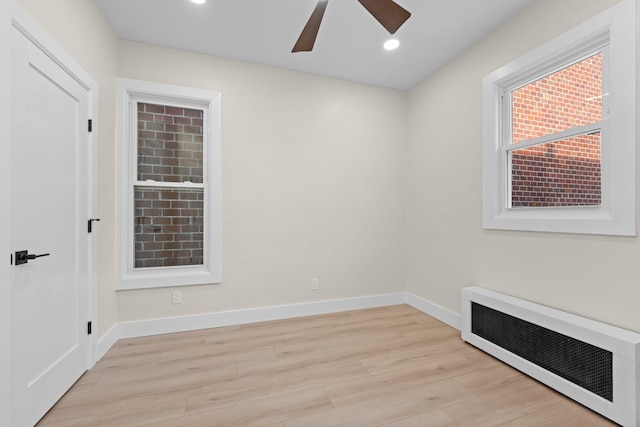 spare room featuring radiator heating unit, ceiling fan, and light wood-type flooring