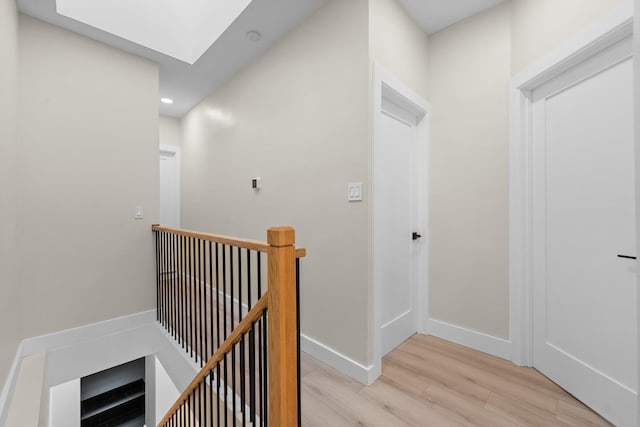 hall with a skylight and light wood-type flooring