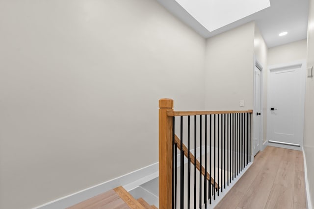 corridor featuring light hardwood / wood-style floors and a skylight