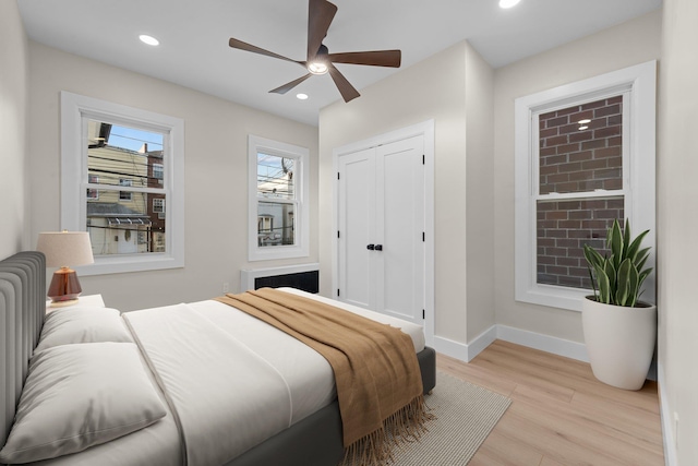 bedroom featuring ceiling fan, light hardwood / wood-style floors, and a closet