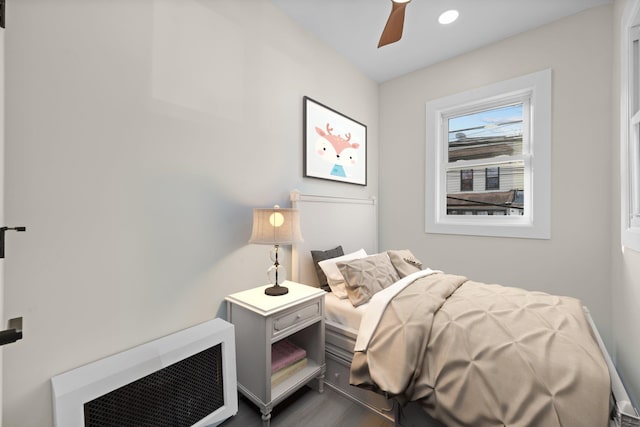 bedroom featuring hardwood / wood-style flooring, heating unit, and ceiling fan