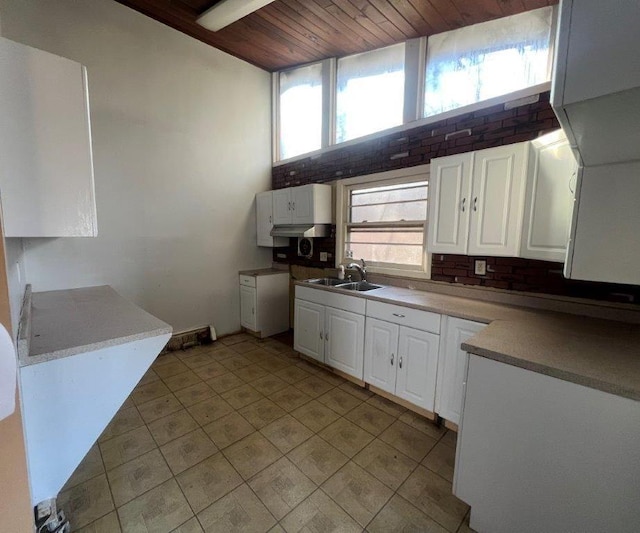 kitchen featuring brick wall, white cabinetry, wooden ceiling, and sink