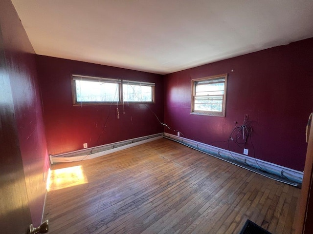 spare room featuring hardwood / wood-style floors, plenty of natural light, and a baseboard heating unit