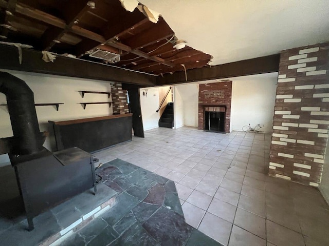 basement with a wood stove and a brick fireplace