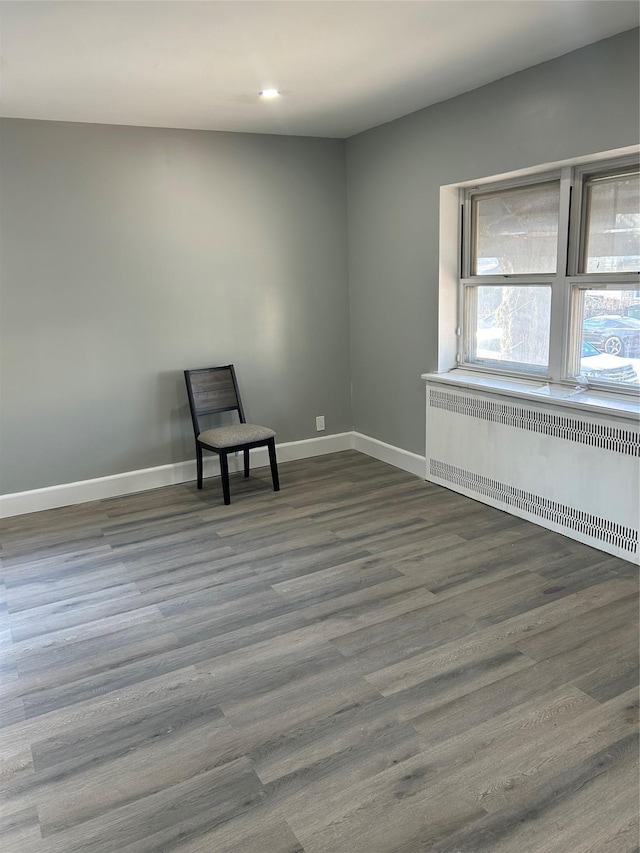 unfurnished room with radiator and dark wood-type flooring