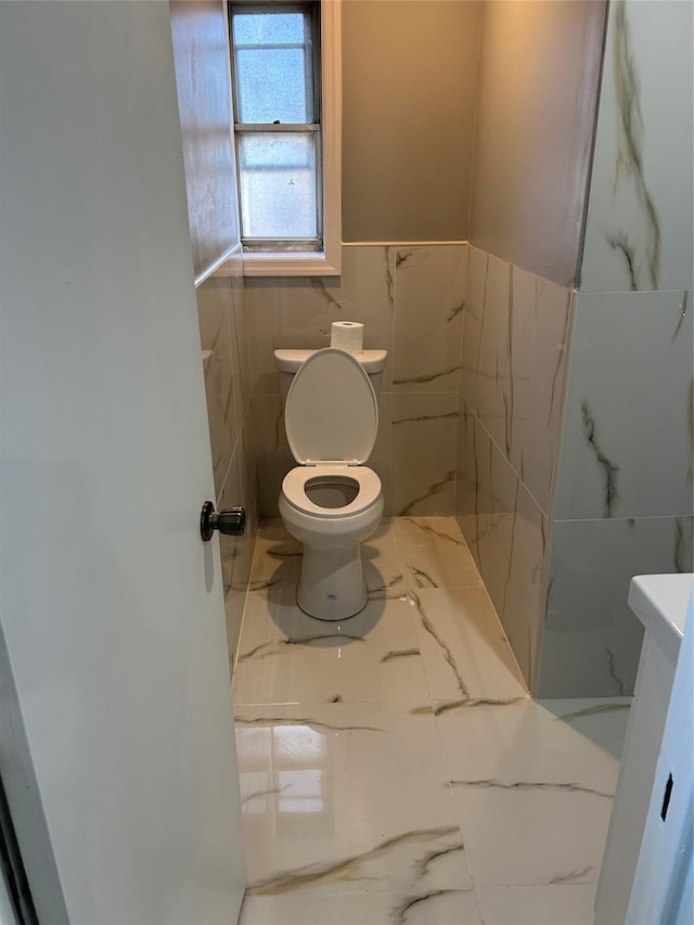 bathroom featuring toilet and tile walls