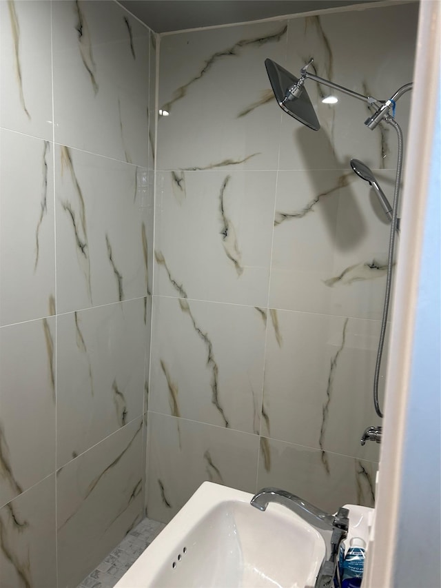 bathroom with tiled shower and sink