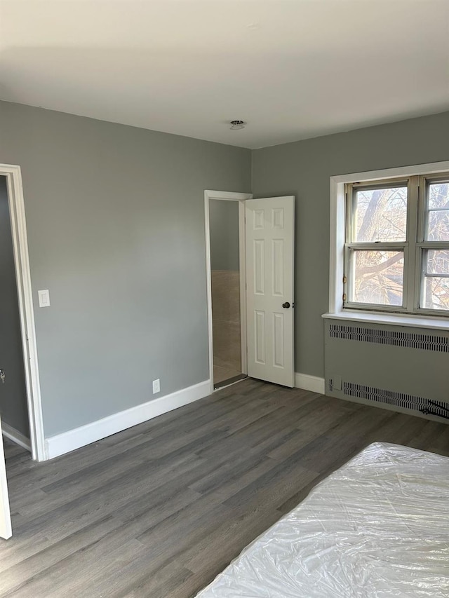 bedroom with radiator heating unit and dark wood-type flooring