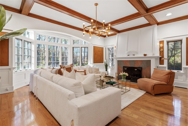 living room featuring an inviting chandelier, coffered ceiling, a tiled fireplace, beam ceiling, and light hardwood / wood-style flooring