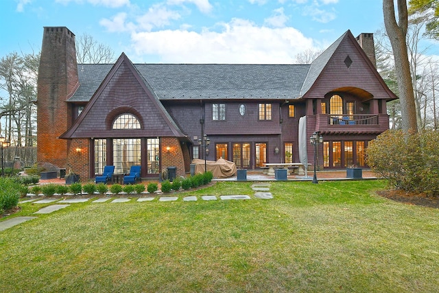 back of house featuring a yard, french doors, a balcony, and a patio