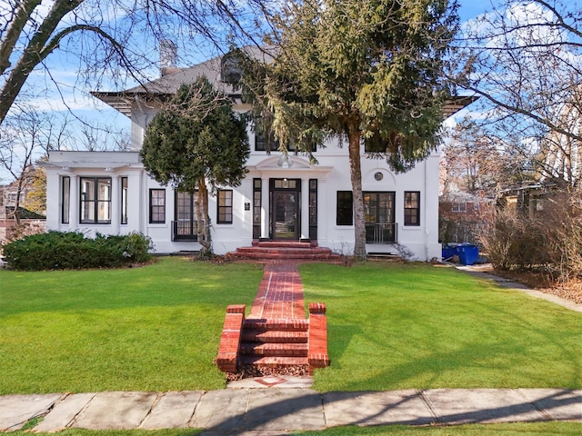 view of front of house with stucco siding, a chimney, and a front yard