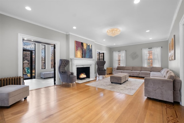 living area featuring light wood-type flooring, radiator, recessed lighting, and a premium fireplace