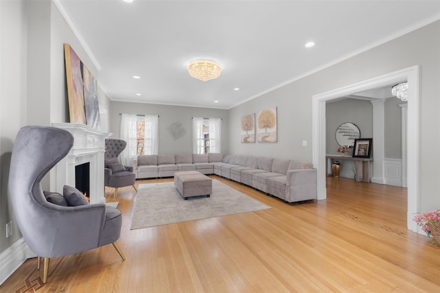 living room with light wood-style floors, recessed lighting, ornamental molding, and a high end fireplace